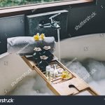 stock-photo-beauty-products-on-tray-on-bathtub-bath-with-foam-is-filling-with-water-relaxing-in-bali-luxury-1546714766