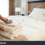 stock-photo-hands-of-hotel-maid-putting-flowers-on-the-stack-of-towels-383952559